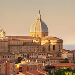 Sonnenuntergang über der Basilika von Loreto, Italien. Die Kuppel und der Glockenturm ragen über die Dächer der Stadt auf.
