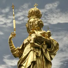 Goldene Statue der Muttergottes mit Kind, dem Patron von Bayern, vor dramatischem Wolkenhimmel.