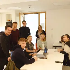 Eine Gruppe junger Leute im Sophie Barat Haus, einige lächelnd, andere am Laptop.