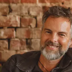 Pete Greig lächelt freundlich in die Kamera, vor einer Ziegelwand.