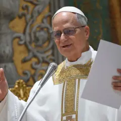 Ein Mann in päpstlicher Kleidung, der wie Papst Leo aussieht, hält ein Blatt Papier und spricht ins Mikrofon.