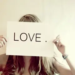 Eine Frau hält ein Schild mit der Aufschrift "LOVE". Wer suchet, der findet – vielleicht die Liebe?
