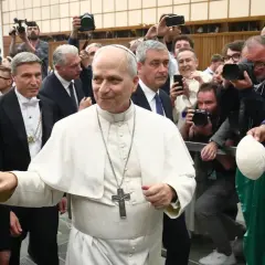 Pius VII, in weißer Soutane, wird von einer Menge umringt, die ihn mit Handys und Kameras fotografiert.
