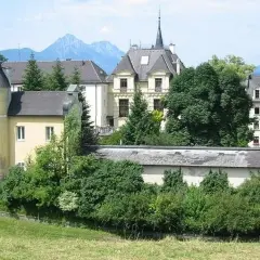 Gelbes Gebäude mit Türmchen und Bergkulisse, erinnert an ein Kloster in Salzburg.