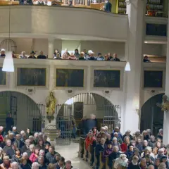 Menschen in der Stadtkirche Wolfratshausen, einige auf der Empore, andere im Kirchenschiff.