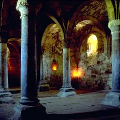 Dunkle, gewölbte Gänge mit steinernen Säulen und Kerzenlicht. Hier könnte man sich fragen: was sind Krypten? Alte unterirdische Räume, oft unter Kirchen.