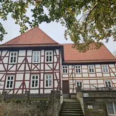 Fachwerkhaus mit roten Ziegeln, das die Wohnung eines Dechanten beherbergt. Ein steinerner Zaun und eine Treppe führen zum Eingang.