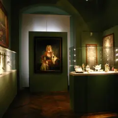 Ausstellung im **Deutschen Orden Wien**: Prunkvolle Waffen, Porträt eines Adligen und feines Silbergeschirr in Vitrinen.