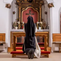 Nonne kniet vor dem Altar. Sie hat sich entschieden, dauerhaft im Kloster zu leben und findet hier ihren Frieden.