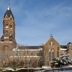 Die Nikolaus Kirche ragt imposant in den blauen Himmel. Schnee bedeckt die Bäume und das Dach der Kirche.
