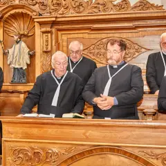 Sechs Geistliche in Soutanen stehen im Chorraum des Stifts Reichersberg.