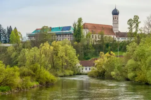 Kloster Beuerberg thront über dem Fluss, umgeben von üppigem Frühlingsgrün. Ein Teil des Klosters wird renoviert.