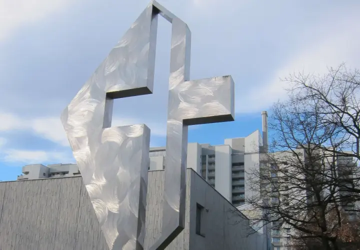 Modernes Kreuz aus gebürstetem Metall vor der Kirche St. Lukas Westkreuz.
