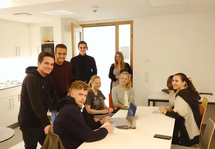 Eine Gruppe junger Leute im Sophie Barat Haus, einige lächelnd, andere am Laptop.