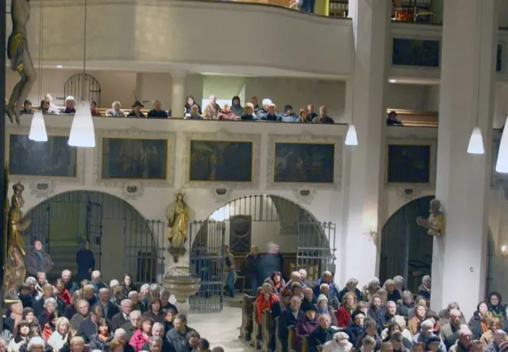 Menschen in der Stadtkirche Wolfratshausen, einige auf der Empore, andere im Kirchenschiff.