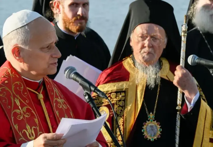 Zwei Geistliche, einer im roten Gewand, der andere mit Bart und Mitra, stehen vor Mikrofonen. Der Mann mit Mitra ist ein Patriarch.