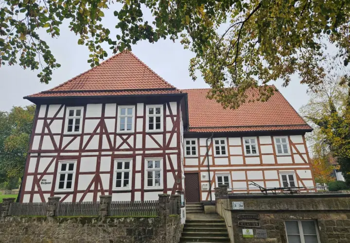 Fachwerkhaus mit roten Ziegeln, das die Wohnung eines Dechanten beherbergt. Ein steinerner Zaun und eine Treppe führen zum Eingang.