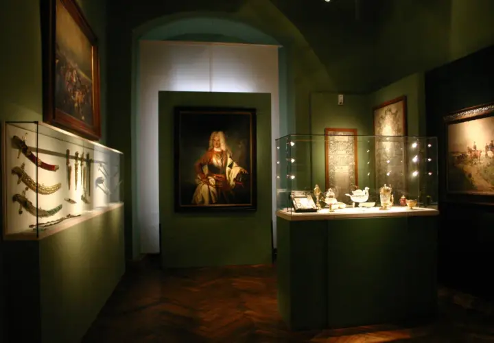 Ausstellung im **Deutschen Orden Wien**: Prunkvolle Waffen, Porträt eines Adligen und feines Silbergeschirr in Vitrinen.