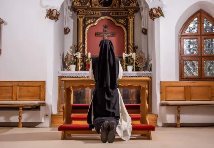 Nonne kniet vor dem Altar. Sie hat sich entschieden, dauerhaft im Kloster zu leben und findet hier ihren Frieden.