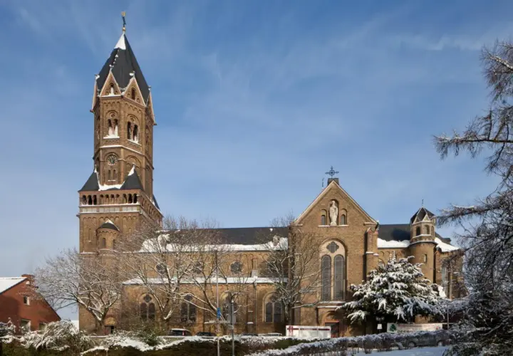 Die Nikolaus Kirche ragt imposant in den blauen Himmel. Schnee bedeckt die Bäume und das Dach der Kirche.