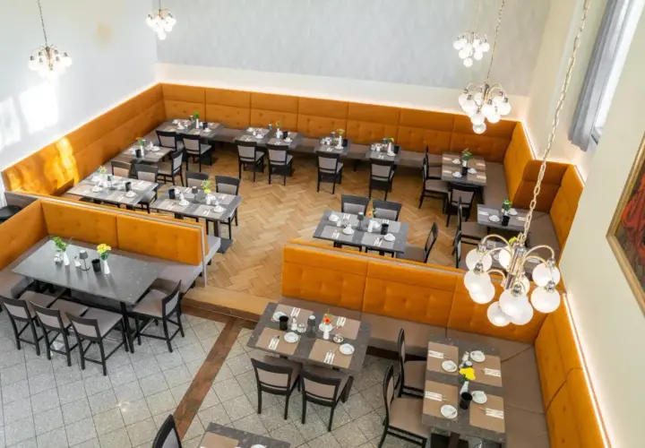 Gemütliche Tische mit Blumenarrangements im Speisesaal des **Pallottiner Salzburg**.