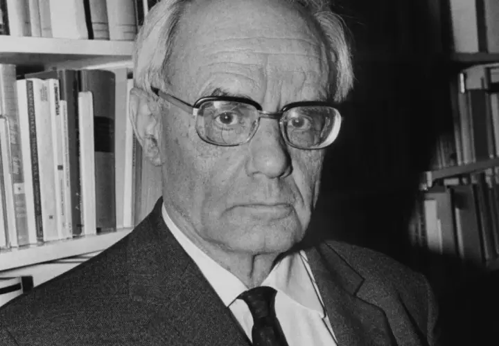 Porträt von Karl Rahner, dem bedeutenden katholischen Theologen, vor einem Bücherregal.