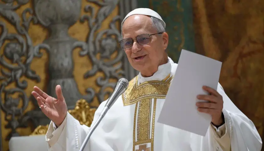 Ein Mann in päpstlicher Kleidung, der wie Papst Leo aussieht, hält ein Blatt Papier und spricht ins Mikrofon.