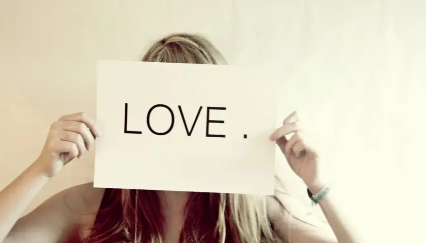 Eine Frau hält ein Schild mit der Aufschrift "LOVE". Wer suchet, der findet – vielleicht die Liebe?