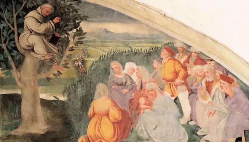 Der heilige Antonius predigt von einem Baum herab einer Gruppe von Menschen.