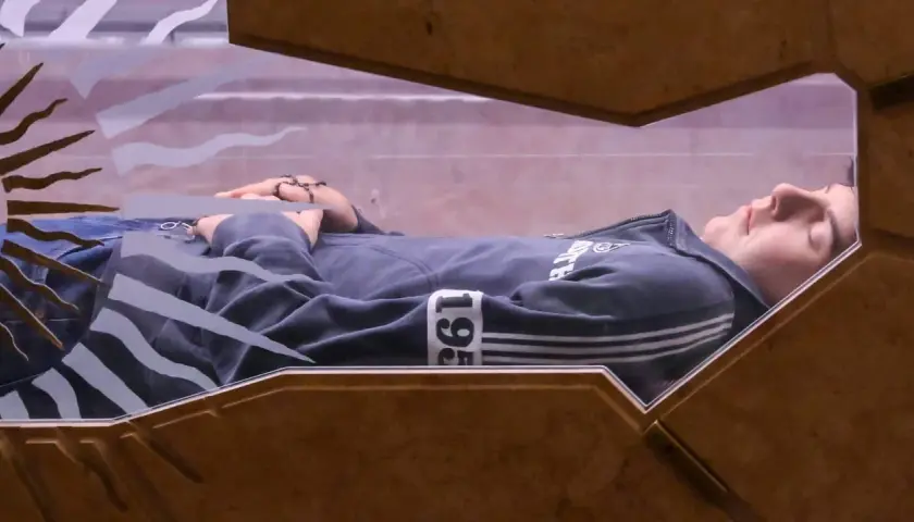 Carlo Acutis ruht in einem gläsernen Sarkophag, seine Hände mit Rosenkranz gefaltet.