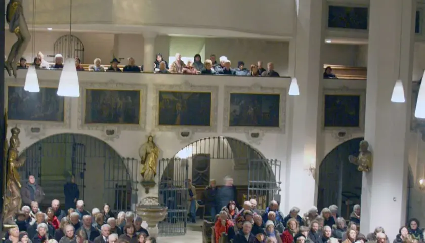 Menschen in der Stadtkirche Wolfratshausen, einige auf der Empore, andere im Kirchenschiff.