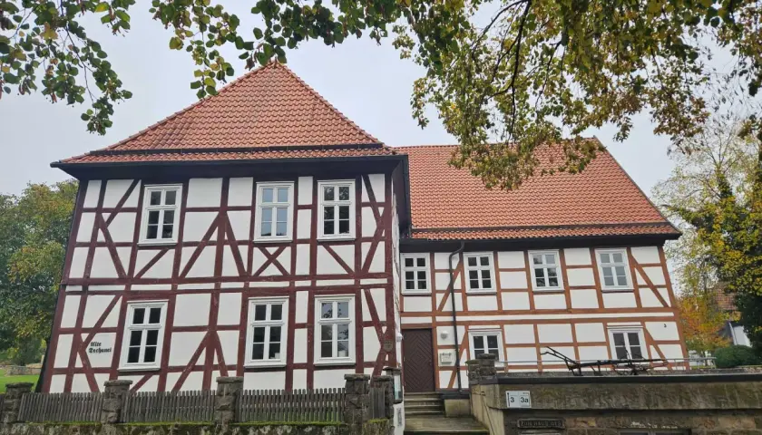 Fachwerkhaus mit roten Ziegeln, das die Wohnung eines Dechanten beherbergt. Ein steinerner Zaun und eine Treppe führen zum Eingang.