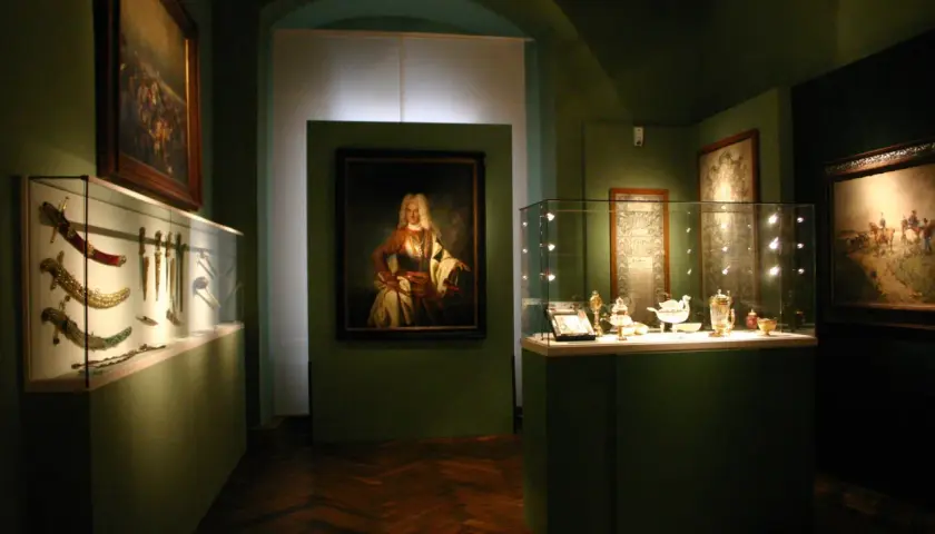 Ausstellung im **Deutschen Orden Wien**: Prunkvolle Waffen, Porträt eines Adligen und feines Silbergeschirr in Vitrinen.