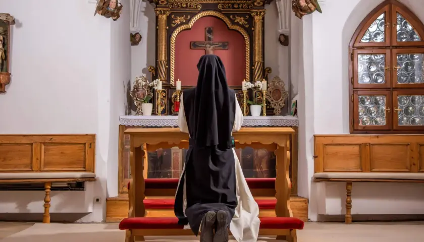 Nonne kniet vor dem Altar. Sie hat sich entschieden, dauerhaft im Kloster zu leben und findet hier ihren Frieden.