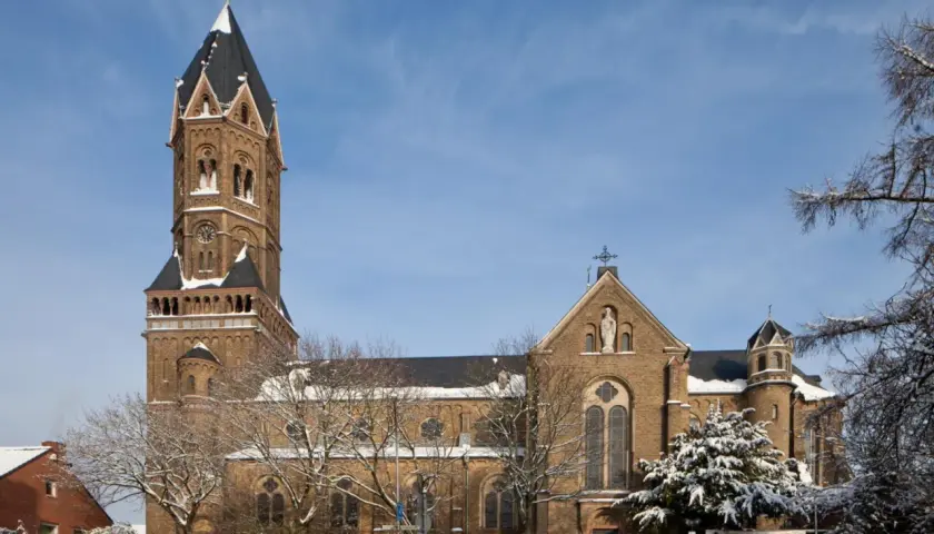 Die Nikolaus Kirche ragt imposant in den blauen Himmel. Schnee bedeckt die Bäume und das Dach der Kirche.