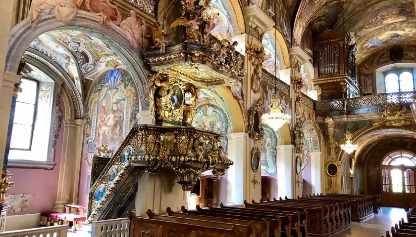 Prachtvoller barocker Innenraum des Stifts Vorau mit kunstvollem Altar, bemalter Decke und Kirchenbänken.