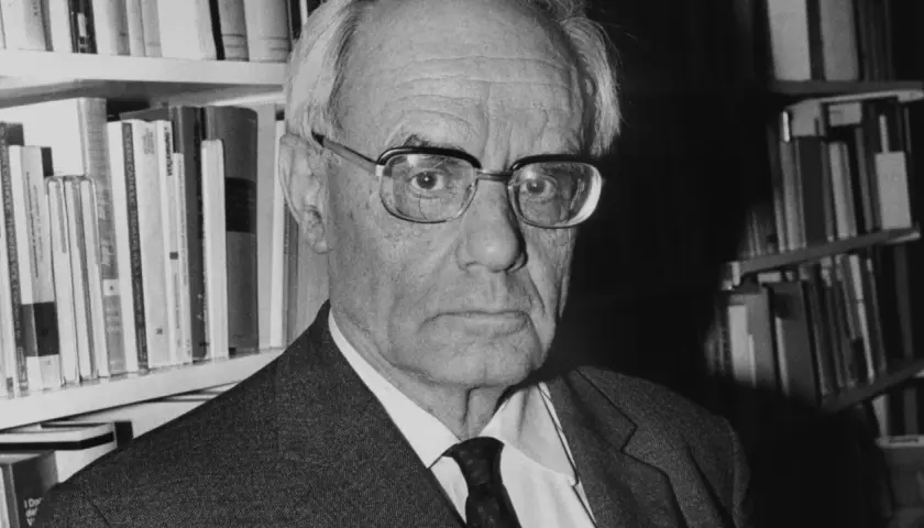 Porträt von Karl Rahner, dem bedeutenden katholischen Theologen, vor einem Bücherregal.