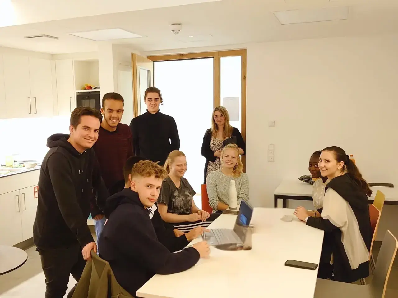 Eine Gruppe junger Leute im Sophie Barat Haus, einige lächelnd, andere am Laptop.