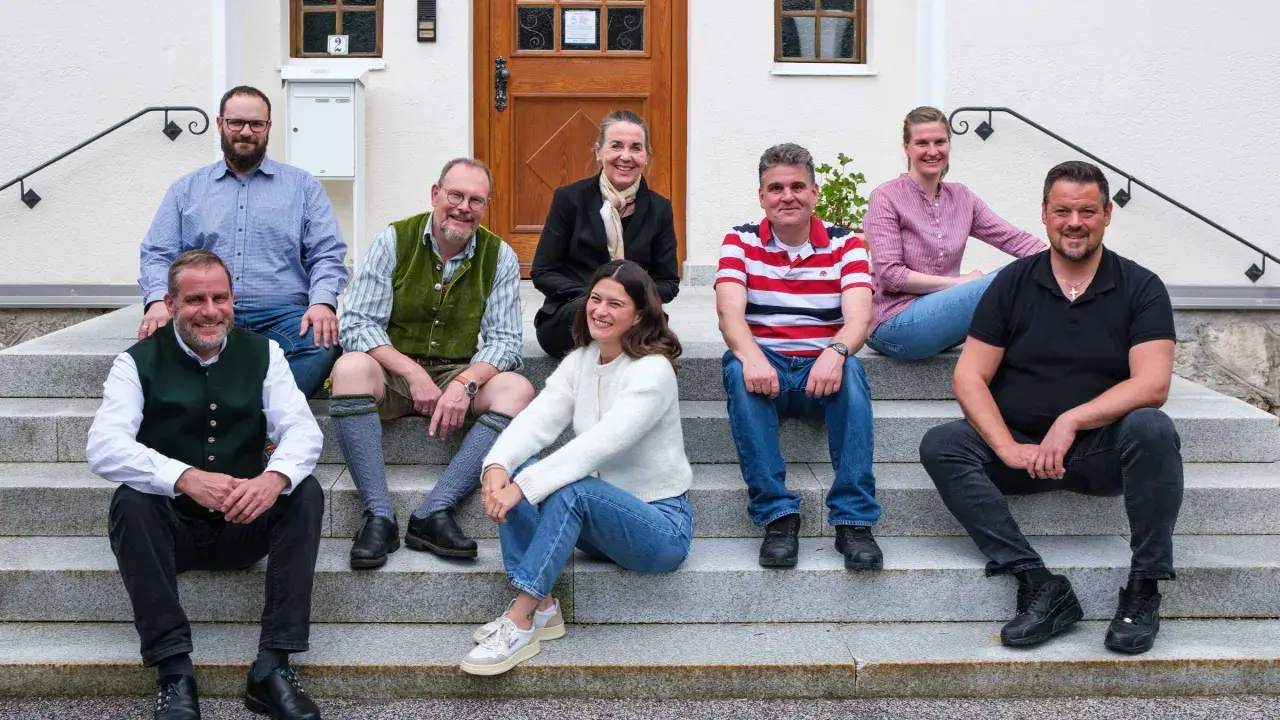Eine Gruppe von Menschen sitzt lächelnd auf einer Treppe. Sie scheinen Teil einer Gemeinschaft zu sein, vielleicht ein Dekanat, das sich für ein Foto versammelt hat.