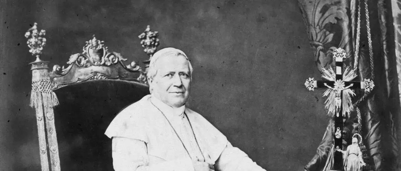 Papst Pius sitzt auf einem prunkvollen Thron, gekleidet in seine Soutane. Neben ihm steht ein aufwendig verziertes Kreuz.
