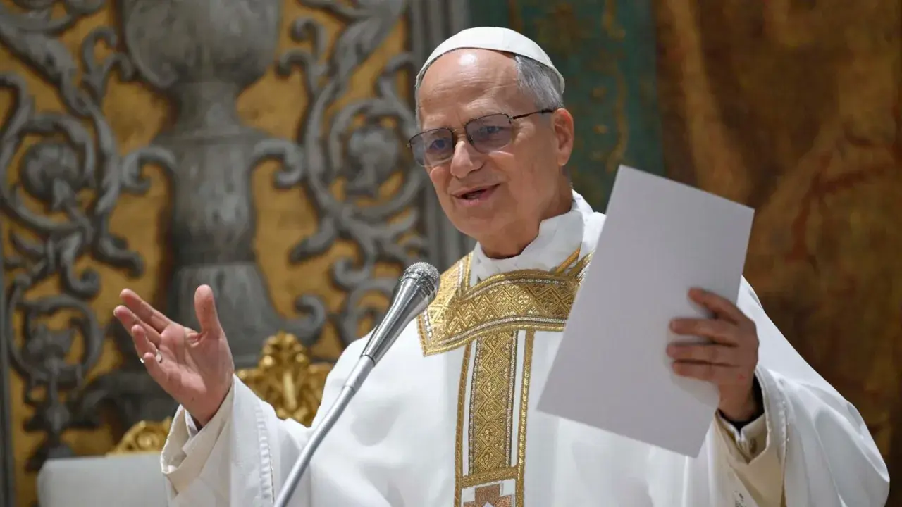 Ein Mann in päpstlicher Kleidung, der wie Papst Leo aussieht, hält ein Blatt Papier und spricht ins Mikrofon.