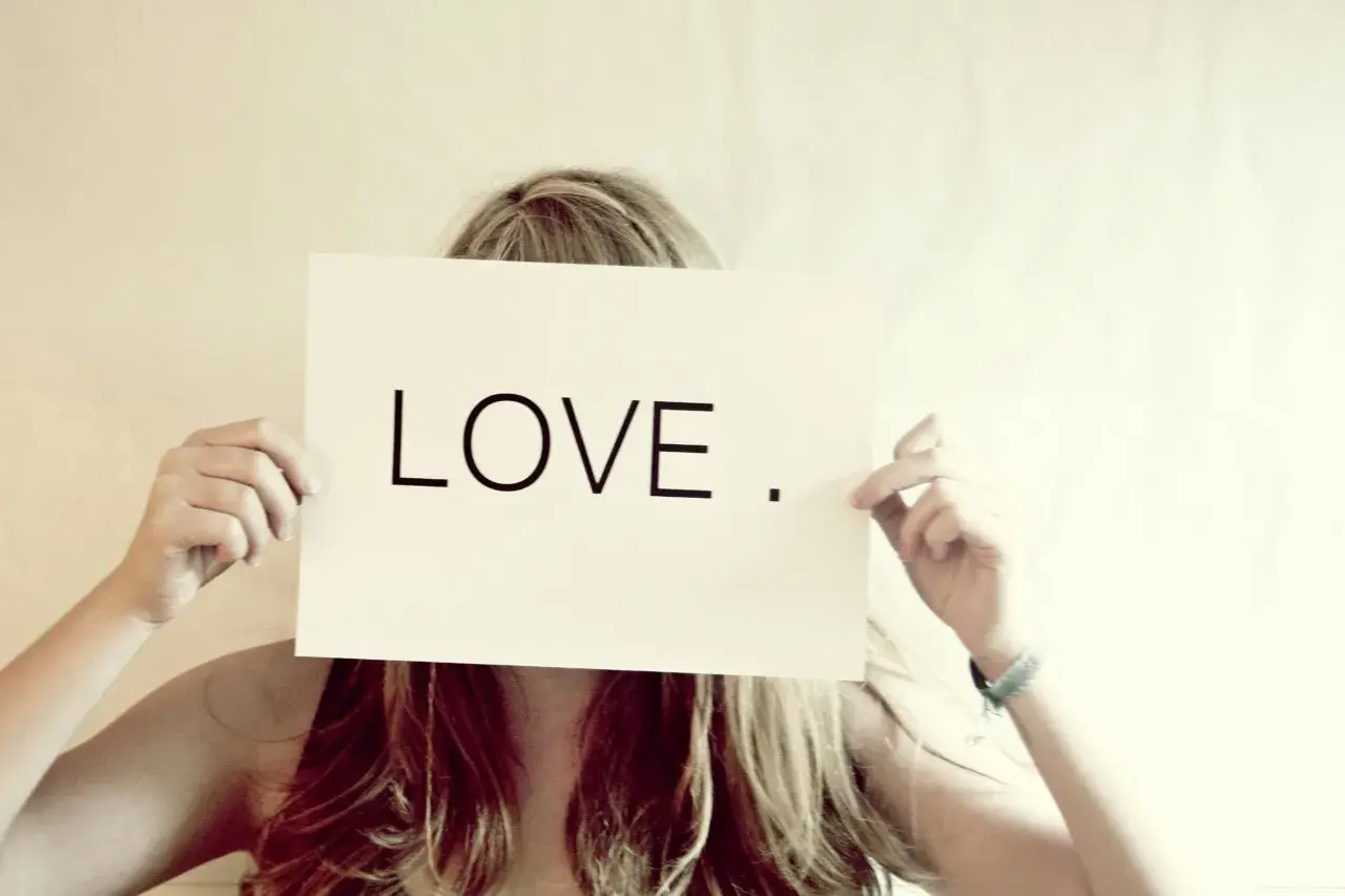 Eine Frau hält ein Schild mit der Aufschrift "LOVE". Wer suchet, der findet – vielleicht die Liebe?