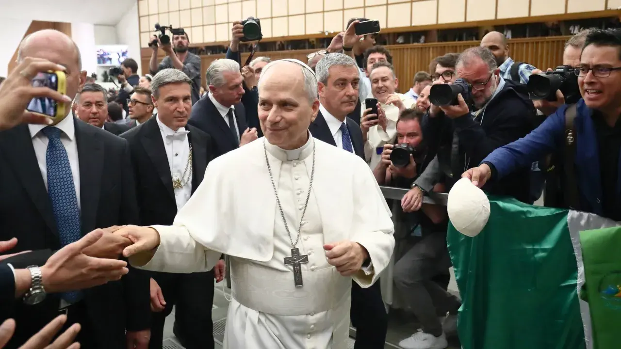Pius VII, in weißer Soutane, wird von einer Menge umringt, die ihn mit Handys und Kameras fotografiert.