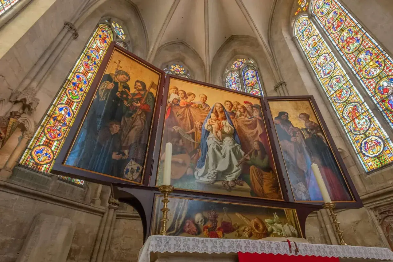 Der Marienaltar im Naumburger Dom zeigt Maria mit Kind, umgeben von Heiligen und Engeln, unter farbenprächtigen Glasfenstern.