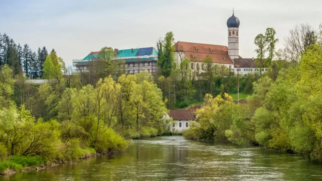 Kloster Beuerberg thront über dem Fluss, umgeben von üppigem Frühlingsgrün. Ein Teil des Klosters wird renoviert.
