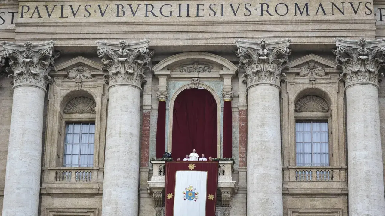 Der Papst steht auf dem Balkon des Petersdoms, umgeben von Kardinälen. Ein großes Wappen hängt über dem Balkon.