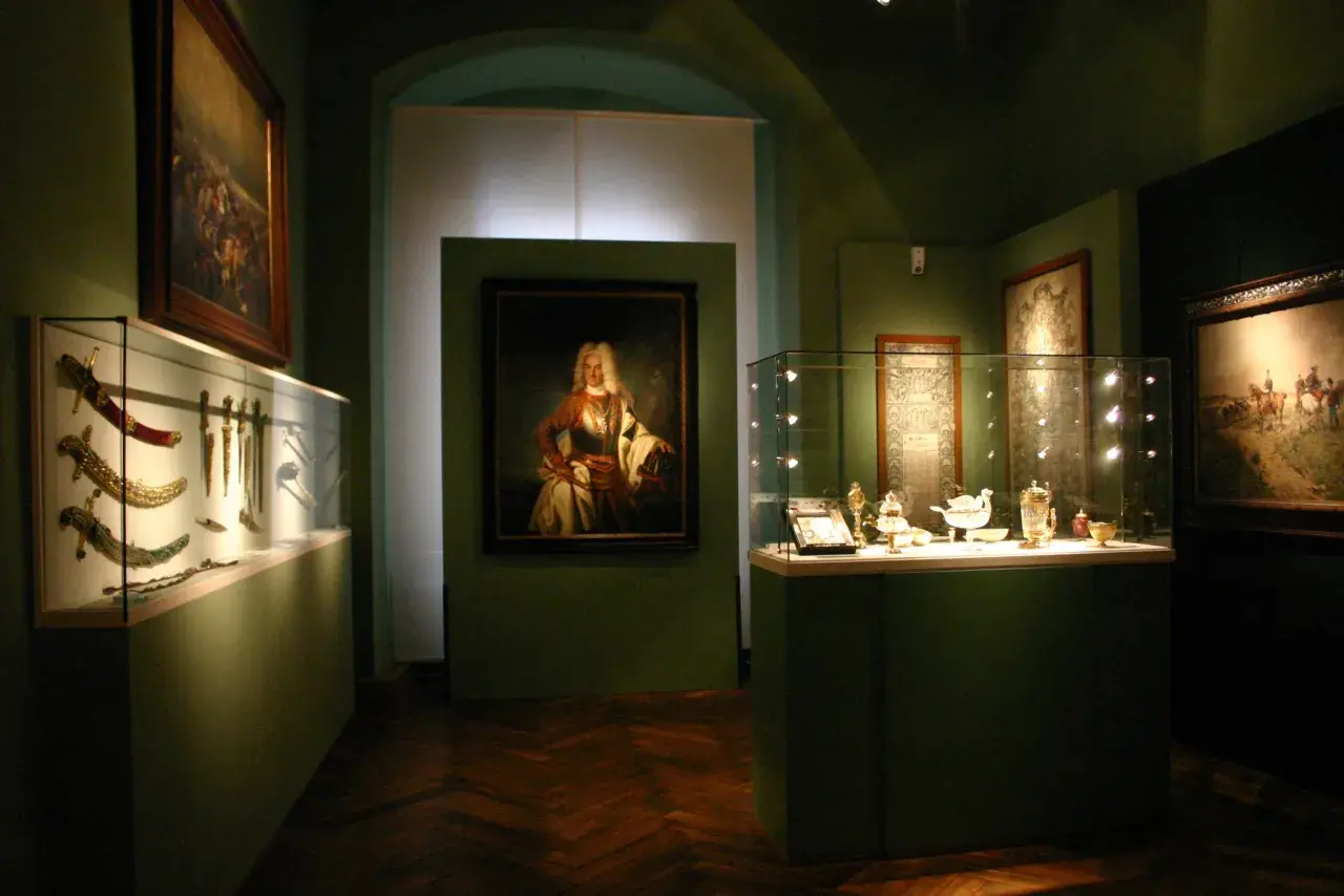 Ausstellung im **Deutschen Orden Wien**: Prunkvolle Waffen, Porträt eines Adligen und feines Silbergeschirr in Vitrinen.