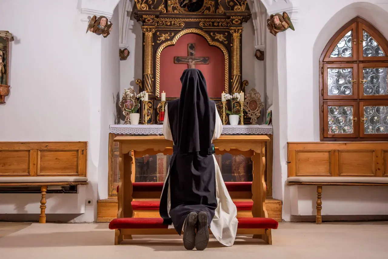 Nonne kniet vor dem Altar. Sie hat sich entschieden, dauerhaft im Kloster zu leben und findet hier ihren Frieden.
