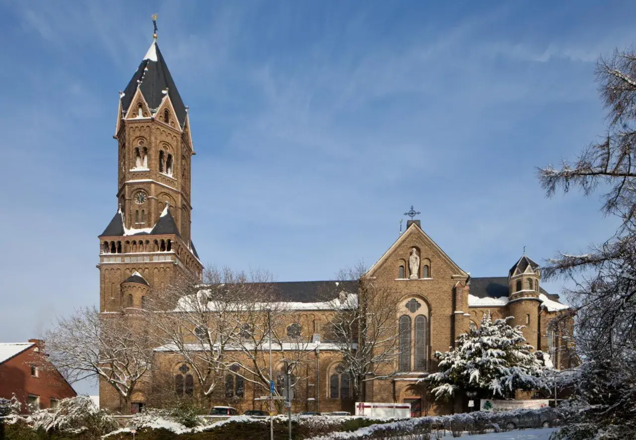 Die Nikolaus Kirche ragt imposant in den blauen Himmel. Schnee bedeckt die Bäume und das Dach der Kirche.