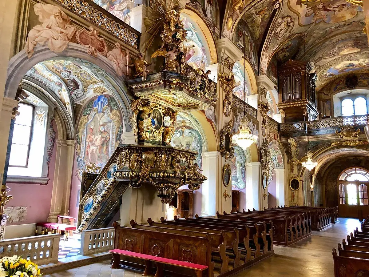 Prachtvoller barocker Innenraum des Stifts Vorau mit kunstvollem Altar, bemalter Decke und Kirchenbänken.